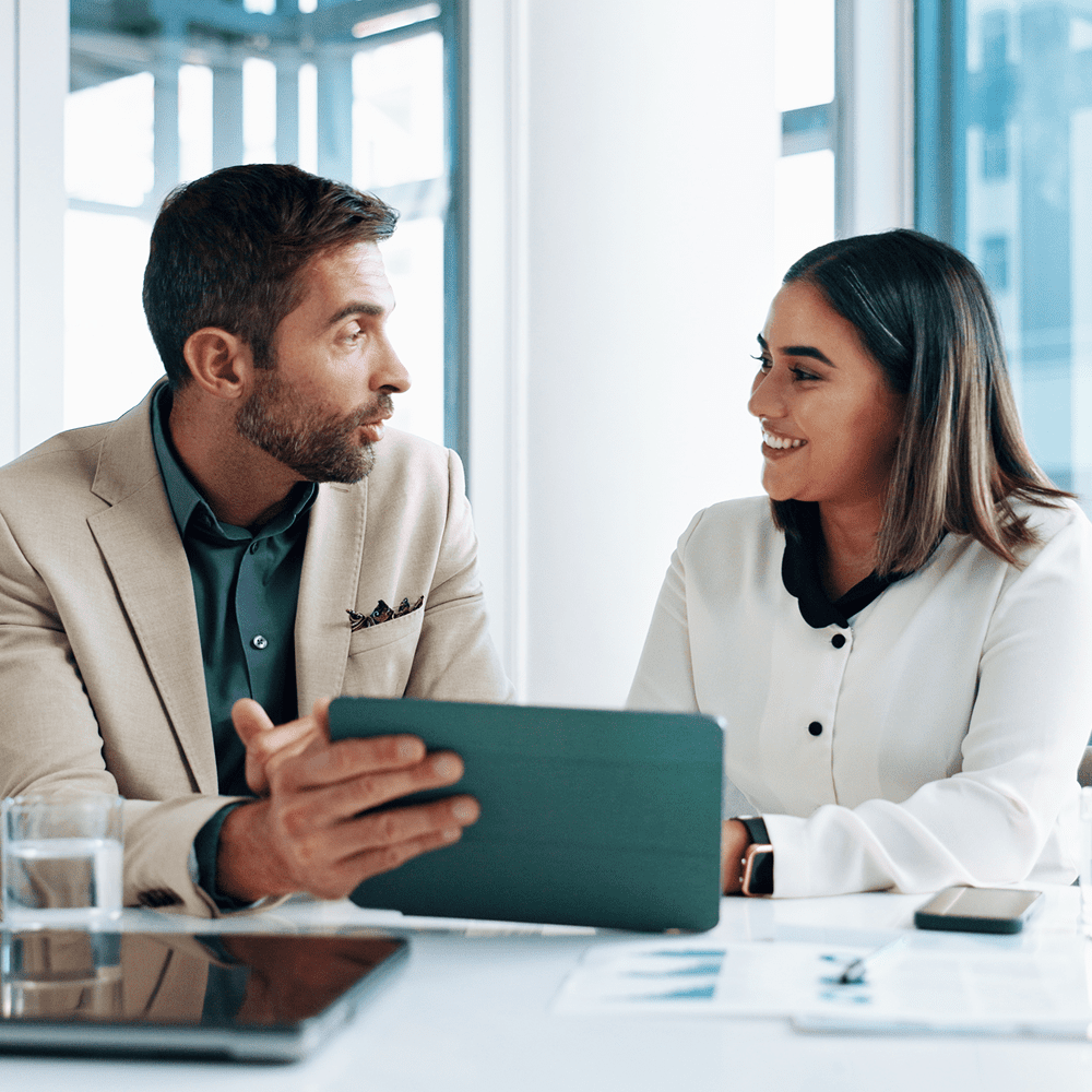 Two colleagues discussing work with a tablet in a modern office.