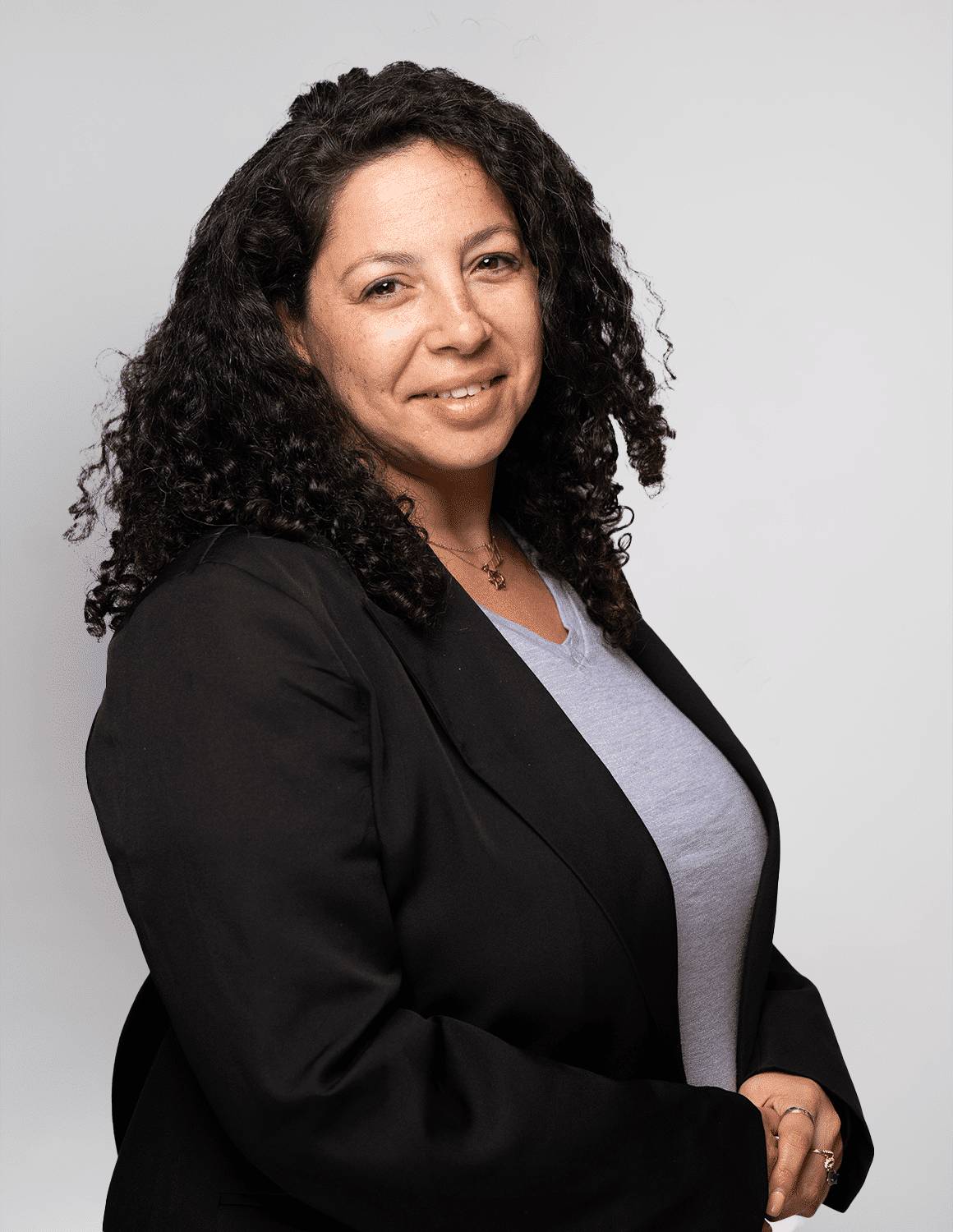 Professional woman with curly hair in a black blazer smiling.